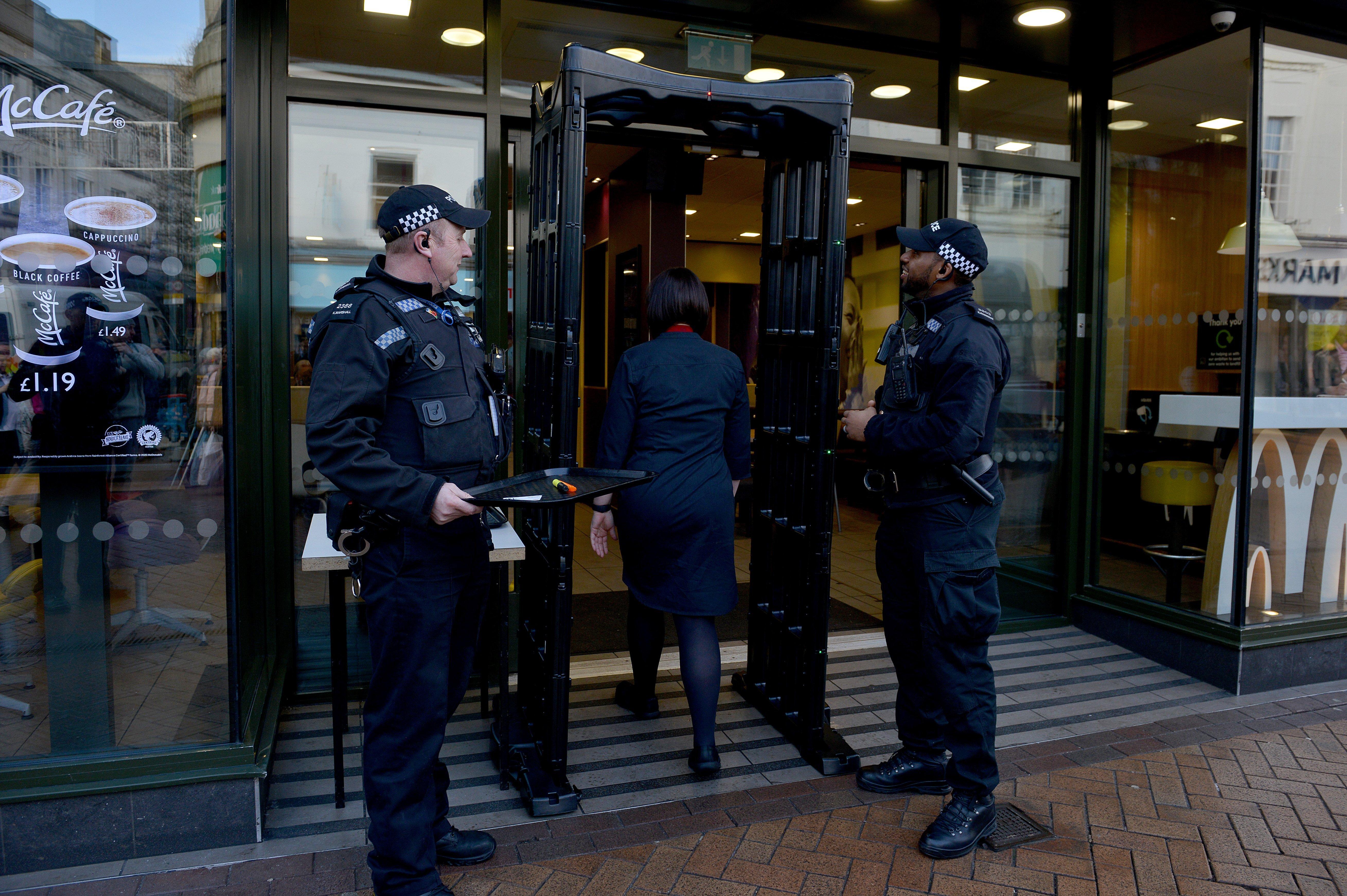 Police officers watch as a customer enters McDonald's on West Gate, Mansfield town centre, through the knife arch.