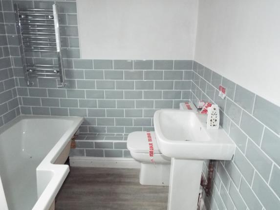 The bathroom comes fitted with a sink, a toilet, and a bath/shower unit.