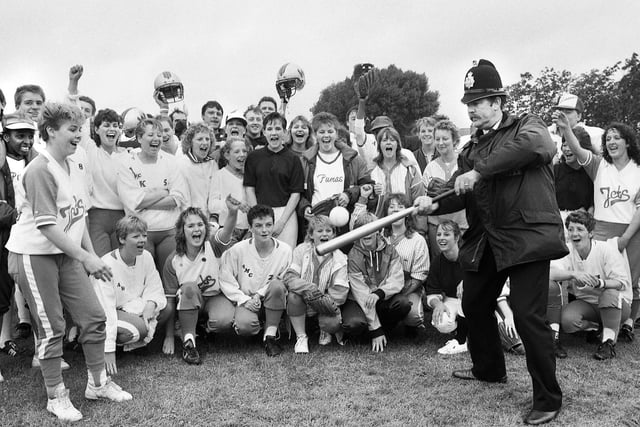 Area Constable Jim Bolton swops his truncheon for a baseball bat with the encouragement of American softball teams and Wigan Wolverines American football team during a fun day at Goose Green in 1987 in aid of the Children's Wheelchair Fund and Wigan Hospice.