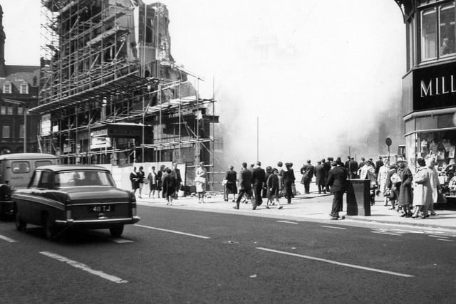 A view from Boar Lane showing the demolition of Royal Exchange Buildings taking place. Several people have stopped to watch.
