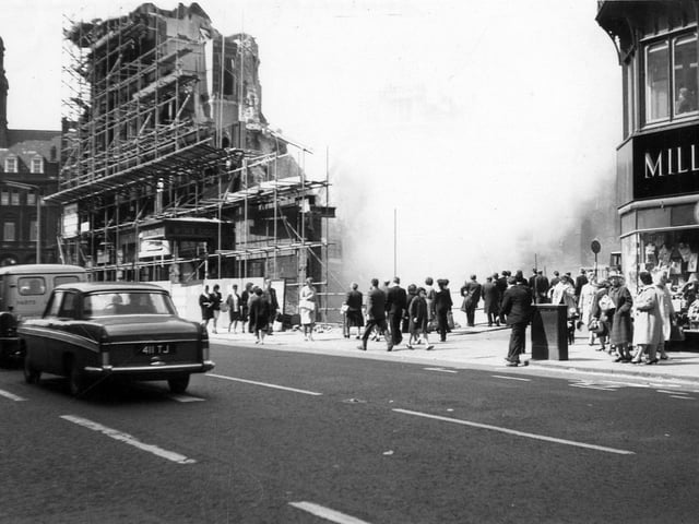 A view from Boar Lane showing the demolition of Royal Exchange Buildings taking place. Several people have stopped to watch.