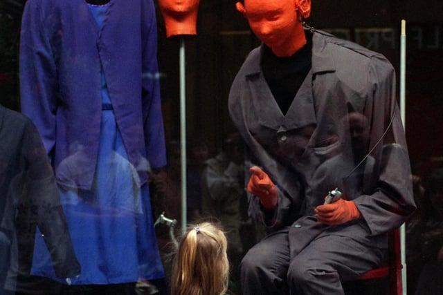 Young Victoria Langford looks at street entertainers Pinheads and Caged Heads during their performance in a shop window at the Victoria Quarter in August 1997.