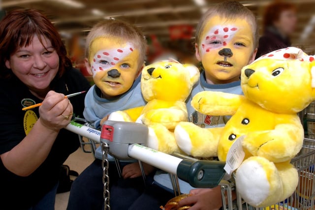 Sharon Ashcroft at Asda, Wigan, paints the faces of twins, Adam and Matthew Ainscough as part of Children In Need 2005.
