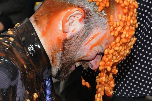 Tutor Chris Peacock sits in a bath of beans, while colleagues and students make donations to tip more beans on him, to raise funds for Children in Need at St John Rigby College, Wigan, in 2015.