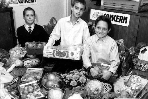 A press photograph of harvest produce collected for Age Concern by children from Love Lane Junior School, Pontefract. From left to right Carl Potter, Mark Crisp and Nicholas Pitts