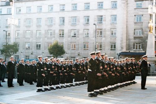 Two rows of sailors from the Ark Royal Guard are visible. Each sailor has a rifle mounted with a bayonet. The Guard's uniform is distinguished from the rest of the crew by having a white belt and white gaiters around the ankles.