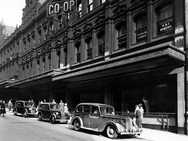 The premises of the Leeds Industrial Co-Operative Society Ltd. on Albion Street pictured in March 1945.. Several cars are parked in front. The nearest (possibly a staff car) has a soldier in the driving seat.