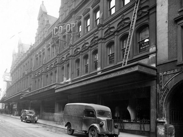 November 1944 and pictured is the Leeds Industrial Co-operative Society. On the building is a large clock and a sign saying Co-op. A Co-op van is parked outside the shop.