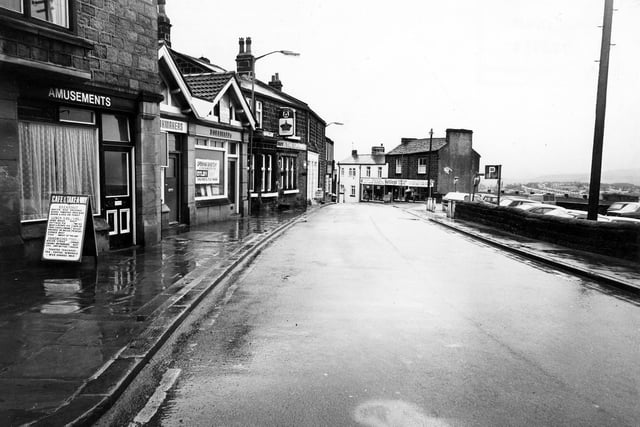 Ivegate looking south in December 1980. At the left edge, built in stone, is number 6 Ivegate with a sign for 'Amusements'. There is a cafe and take-away business here offering cooked breakfasts, lunches and sandwiches.