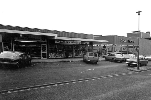 Yeadon High Street in December 1979 with Morrisons supermarket on the right and shops that were built as part of the supermarket complex on the left. These were addressed as Cliffe Court eventually. In a directory for 1980 the Direct Curtain Company is listed as shop unit 3, Morrisons supermarket centre. The company had a workroom in New Briggate, Leeds. In front of the shops is a car parking area for thirty cars.