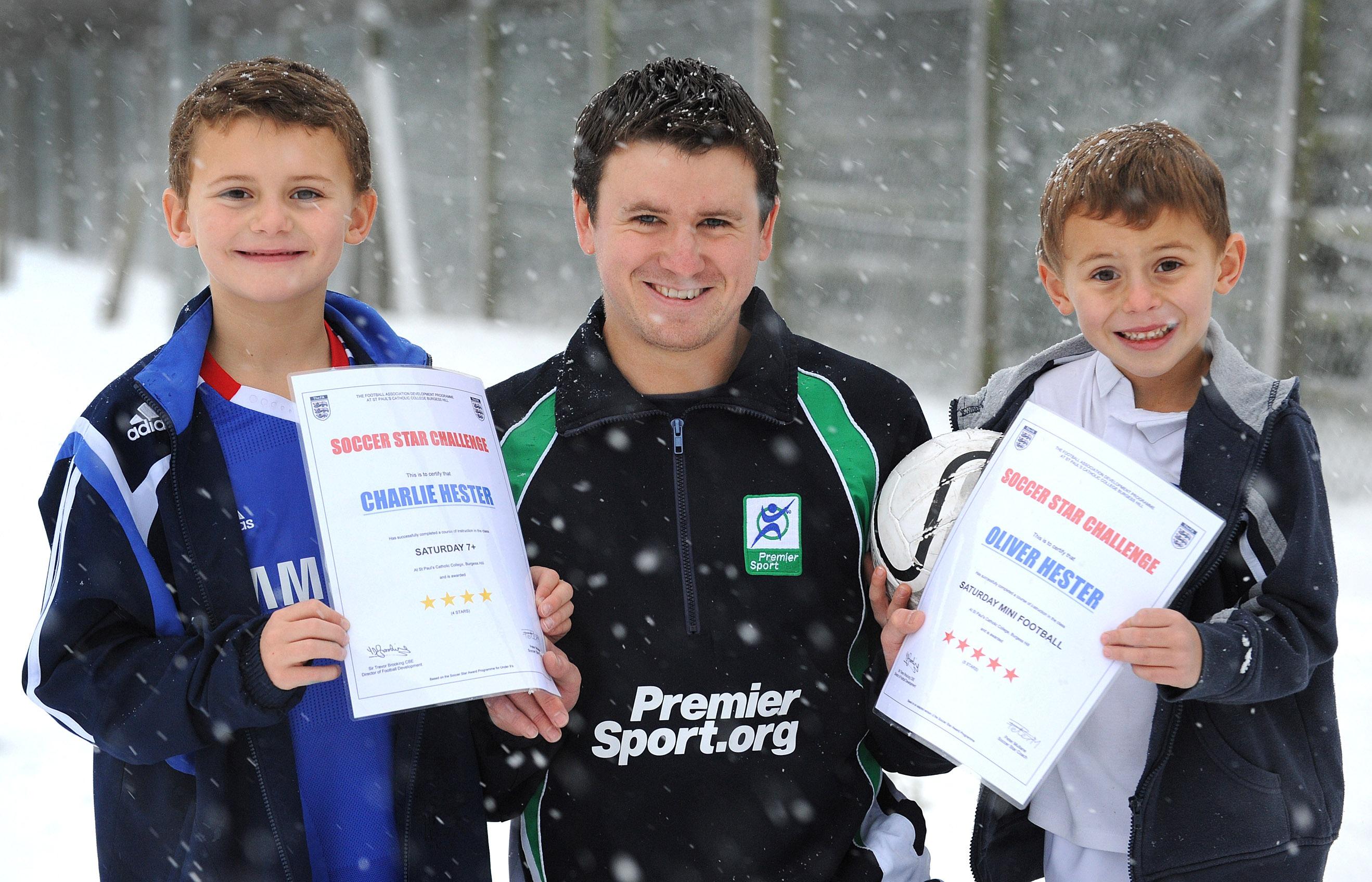Snow hit Burgess Hill on Saturday 18th Dec. Area Co-ordinator Peter Mullane of Premier Sport still managed to run the footballing tuition at St Pauls College. Pictured here with Charlie and Oliver Hester receiving their football skills awards ENGSNL00120101220104545