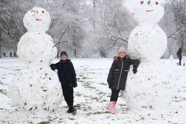 Two very impressive snowmen and two very proud creators. Photo: Getty Images