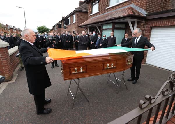 Sean Murray (left) and Gerry Kelly (right) place an Irish flag onto the coffin of senior Irish Republican and former leading IRA figure Bobby Storey ahead of his funeral in west Belfast