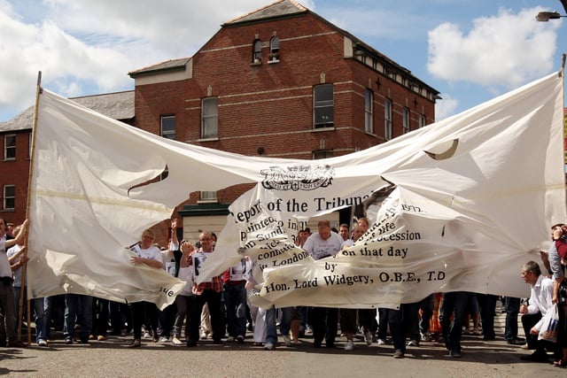 Members of the Bloody Sunday Justice Campaign march through a giant copy of the Widgery Report on their way to the Guildhall to hear the findings of the Saville Report.
