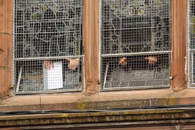 JUNE 15, 2010...  Family members of the victims of the Bloody Sunday shootings give the waiting crowd a 'thumbs up' sign from inside the Guildhall after reading a preview of the findings of the Saville Report.