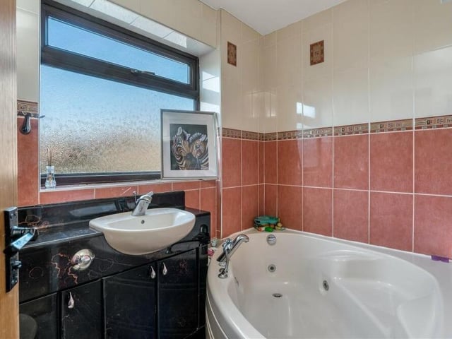 As well as the shower room downstairs, the property includes this sparkling family bathroom on the first floor. A Jacuzzi bath is complemented by a vanity unit, low-flush WC, heated towel-rail, fully tiled walls and spotlights.