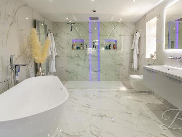 Here is the master bedroom's designer en suite, which includes a standalone bath with waterfall tap, spacious, walk-in shower cubicle, double vanity hand wash unit and low-flush WC. There is even a full-sized, mirrored TV, plus floor-to-ceiling marble tiling, downlights and underfloor heating.