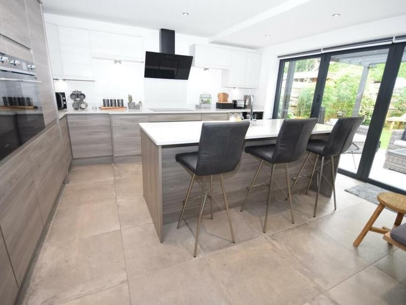 The contemporary kitchen area includes showstopping bi-fold doors that give access to the garden. A feature centre island is inset with sink and drainer and also incorporates a functional breakfast bar with seating.