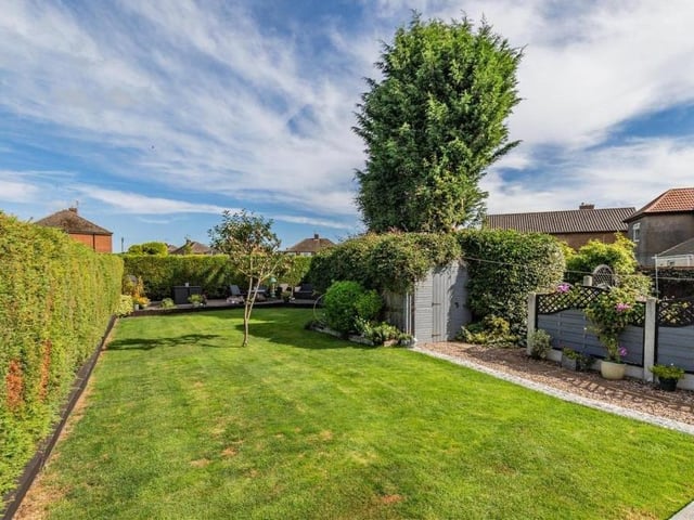 Moving outside now, here is the back garden, with its lawn and apple tree. At the top end of the lawn is a large, decked patio.
