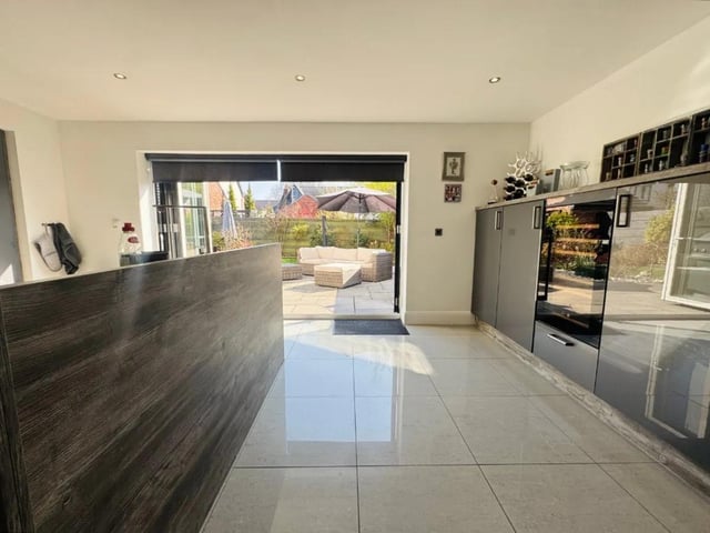 The kitchen has a range of fitted wall and base units, integrated appliances and feature lighting.