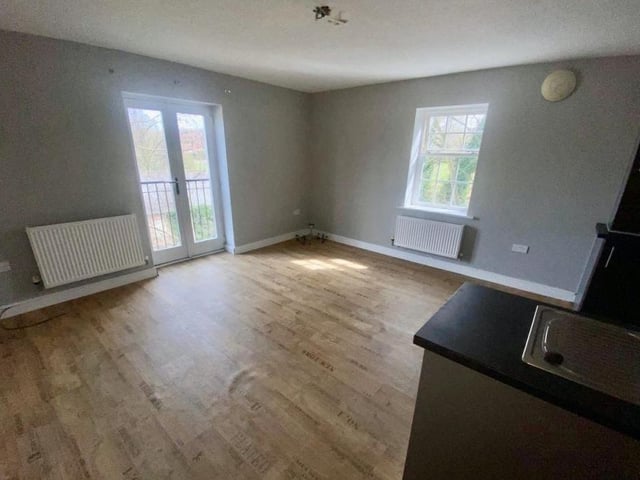 The main room in the apartment is this open-plan living space, which includes the kitchen. A window at the back and French doors to the side make it bright and cheerful.