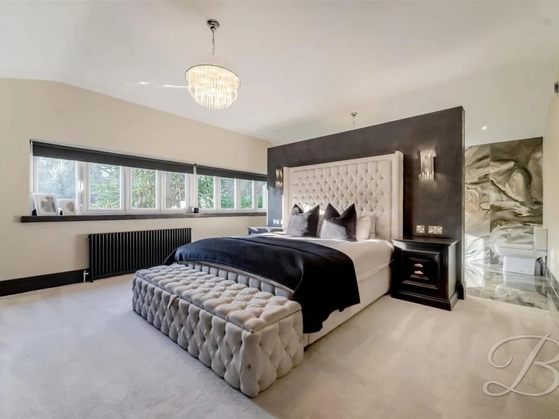 A spacious bedroom with ample room, plush carpets, and central heating for year-round comfort. Built-in wardrobes provide practical storage, and a wall subtly divides the en suite, offering privacy while maintaining a unique connection between the bedroom and bathroom.