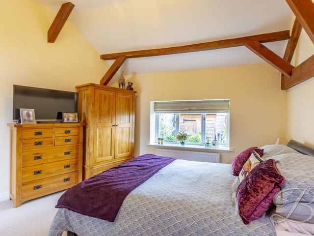 Character features persist in the master bedroom, which has exposed ceiling beams. There is a carpeted floor, a window facing the front of the property and access to an en suite.