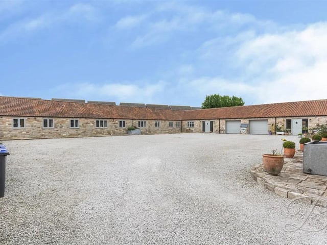 The striking and spacious property boasts a graveled driveway and a garage, providing excellent off-street parking.