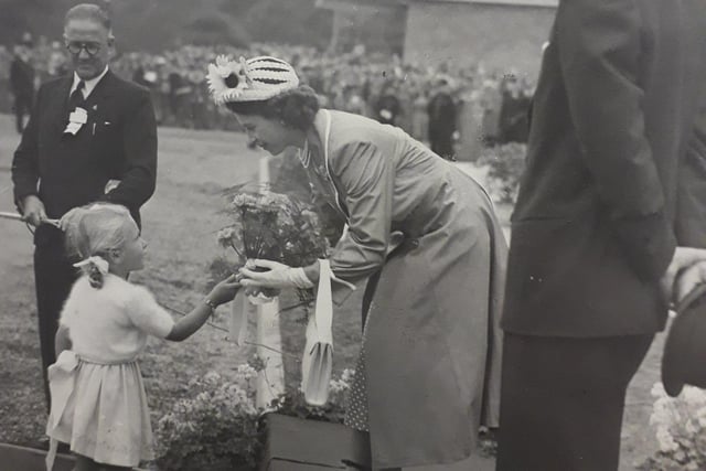Princess Elizabeth receives a posy of flowers from a young child at Portland Training College in 1949.