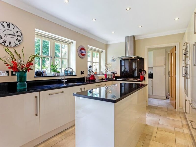 A range of integrated appliances within the dining kitchen include a Neff five-burner gas hob with extractor above,a Neff microwave, a Neff electric fan, a fridge and freezer, and a Neff dishwasher. There is also a stainless steel sink and drainer, while in the background, you can see a door to the utility room, where there is space and plumbing for a washing machine and dryer, as well as larder storage.