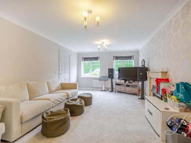 Completed with carpeted flooring, this room offers access from the dining room, a fireplace, a central heating radiator, and two windows overlooking the front of the property, perfect for cosy family evenings.