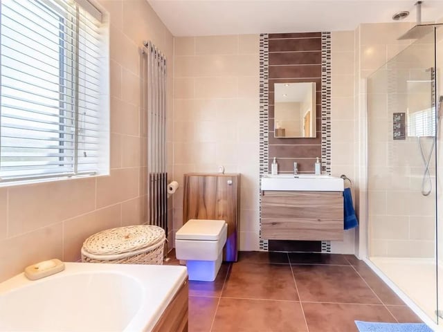 A beautifully appointed modern bathroom with bathtub, separate, large tiled shower enclosure with ceiling mounted rainfall shower.