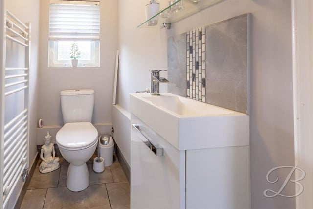 Completing our tour of the ground floor at the £650,000-plus property is this toilet. It comprises a low-flush WC, vanity unit with wash hand basin, heated towel-rail and tiled flooring.