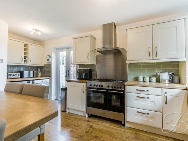 The attractive kitchen comes with a range of integrated appliances, plus space for additional ones too. The door you can see gives access to the side of the property.
