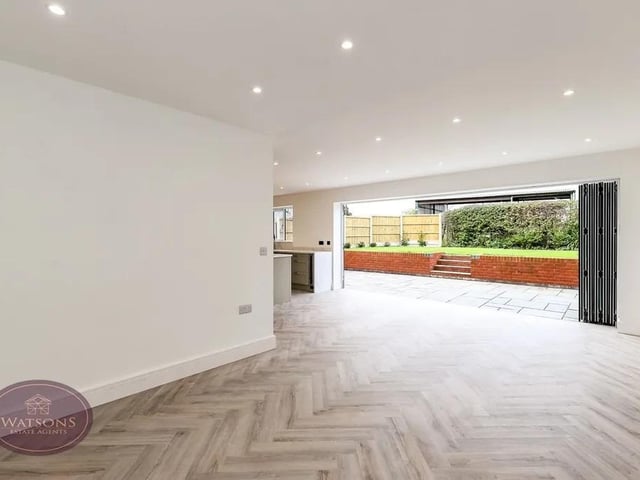 The spacious open plan living space features laminate wood flooring with underfloor heating and  aluminium bi-fold doors to the rear garden