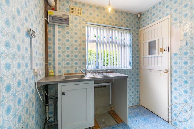 Next door to the kitchen is this small but handy utility room. It has space and plumbing for additional appliances, plus an inset sink and drainer.