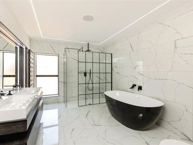 One of the stunning ensuite bathrooms in the property with roll top bath and shower.