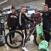 Hayden Hudson sat on his new bike with (l to r) Tracey Hudson, Victoria Walton (Frasers Group) and David Fletcher (Evans Cycles Store Manager) stood behind.