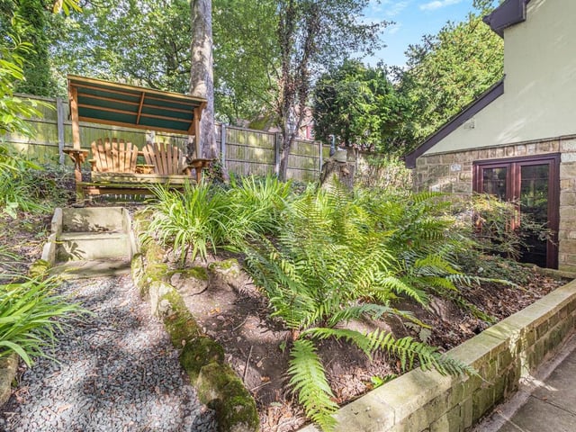 Another enchanting corner of the garden, with raised beds and steps leading to a seating area.