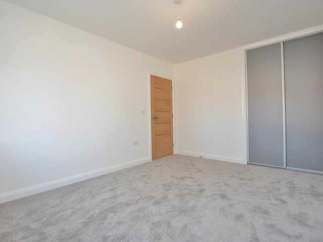 The first bedroom from a different angle, which shows its fitted wardrobes with a hanging rail, shelving and sliding 'soft closing' doors.