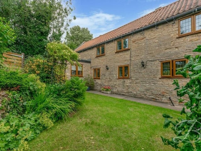 The beautifully landscaped garden at the £350,000 Warsop property features a lawn and mature planted borders.