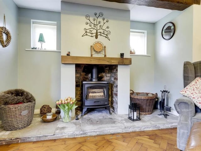 The living room boasts an impressive inglenook fireplace housing a cosy log burner, perfect for relaxing evenings.