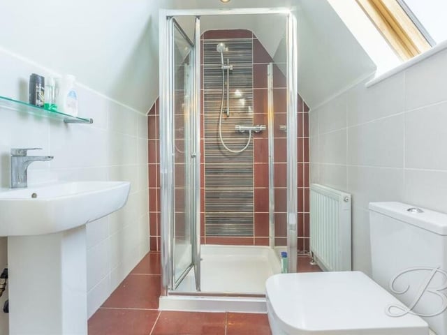 The fourth bedroom has access to this en suite shower room. It has an enclosed shower, low-flush WC, pedestal sink and a Velux window.