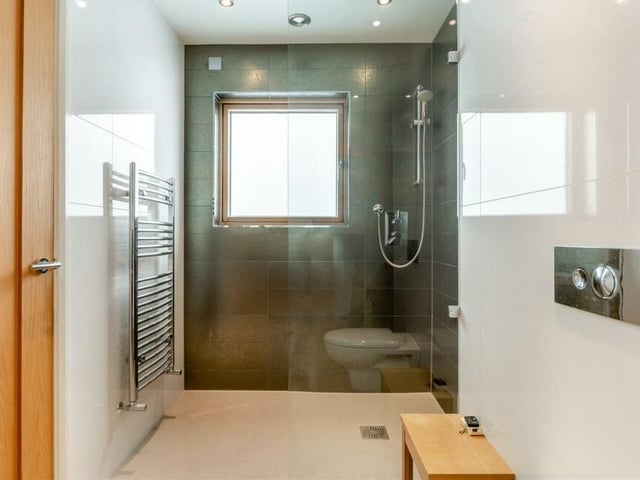Accessed from the gym or fifth bedroom is this beautifully appointed Jack and Jill wet room by Porcelanosa. It includes a walk-in, tiled shower area with Grohe shower, wall-hung, low-flush WC and chrome, heated towel-rail.