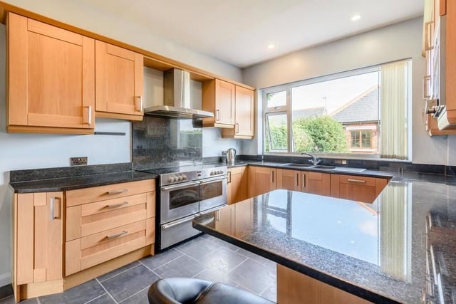 Let's move on now into the breakfast kitchen, which features oak cabinets comprising wall cupboards, base units and drawers with brushed metal handles, and black granite worktops. There is also a breakfast bar, large one-and-a-half bowl sink and space for a range cooker.