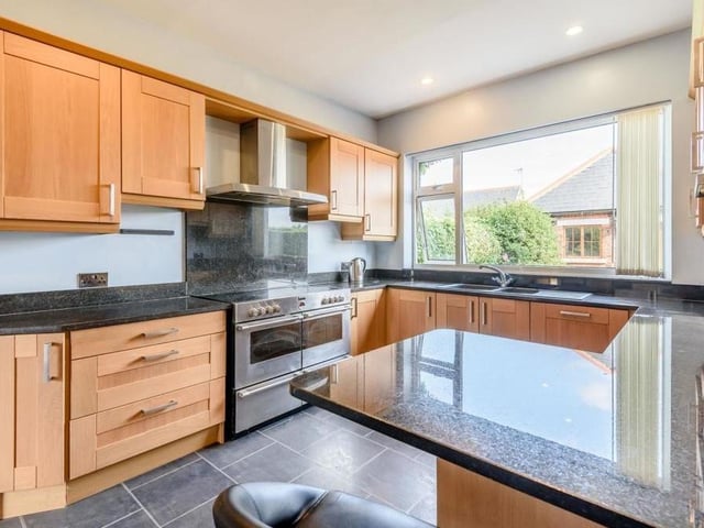 Let's move on now into the breakfast kitchen, which features oak cabinets comprising wall cupboards, base units and drawers with brushed metal handles, and black granite worktops. There is also a breakfast bar, large one-and-a-half bowl sink and space for a range cooker.