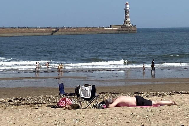 A sunbather makes the most of the warmth down on the sand at Roker.