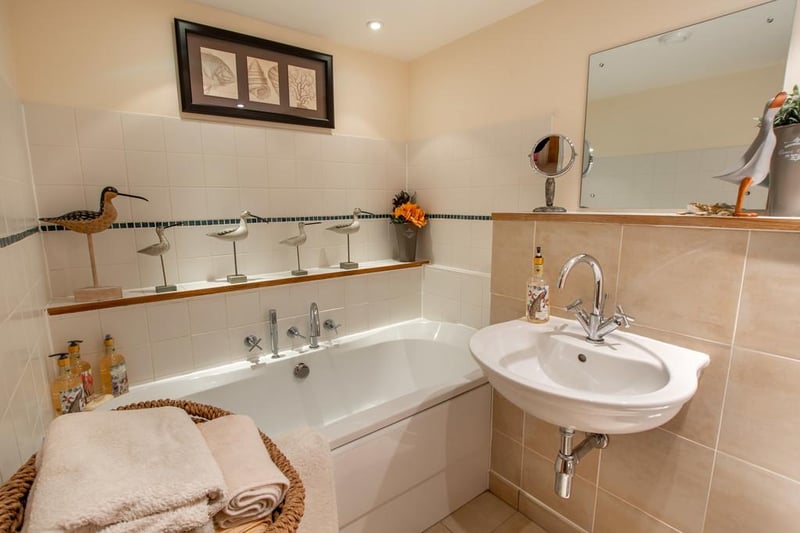 The family bathroom features a white suite - there's a bath with chrome shower attachment, wall mounted wash basin, heated towel rail and low flush WC.