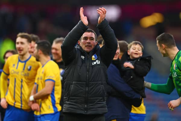Nigel Clough applauds fans on the pitch after the FA Cup fourth round football match between Burnley and Mansfield Town at Turf Moor in Burnley on February 14, 2026. (Photo by Paul Currie / AFP via Getty Images)
