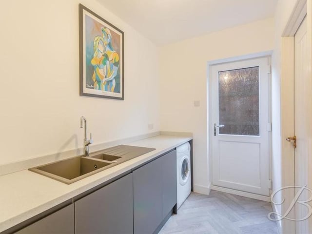 This utility room can also be found on the ground floor. It consists of cabinets, a work surface, inset sink with mixer tap above, and space and plumbing for a washing machine.